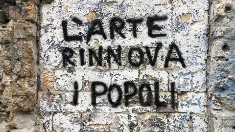 Ein Graffito auf einer Backsteinwand mit der Aufschrift "Il arte rinnova i popoli"