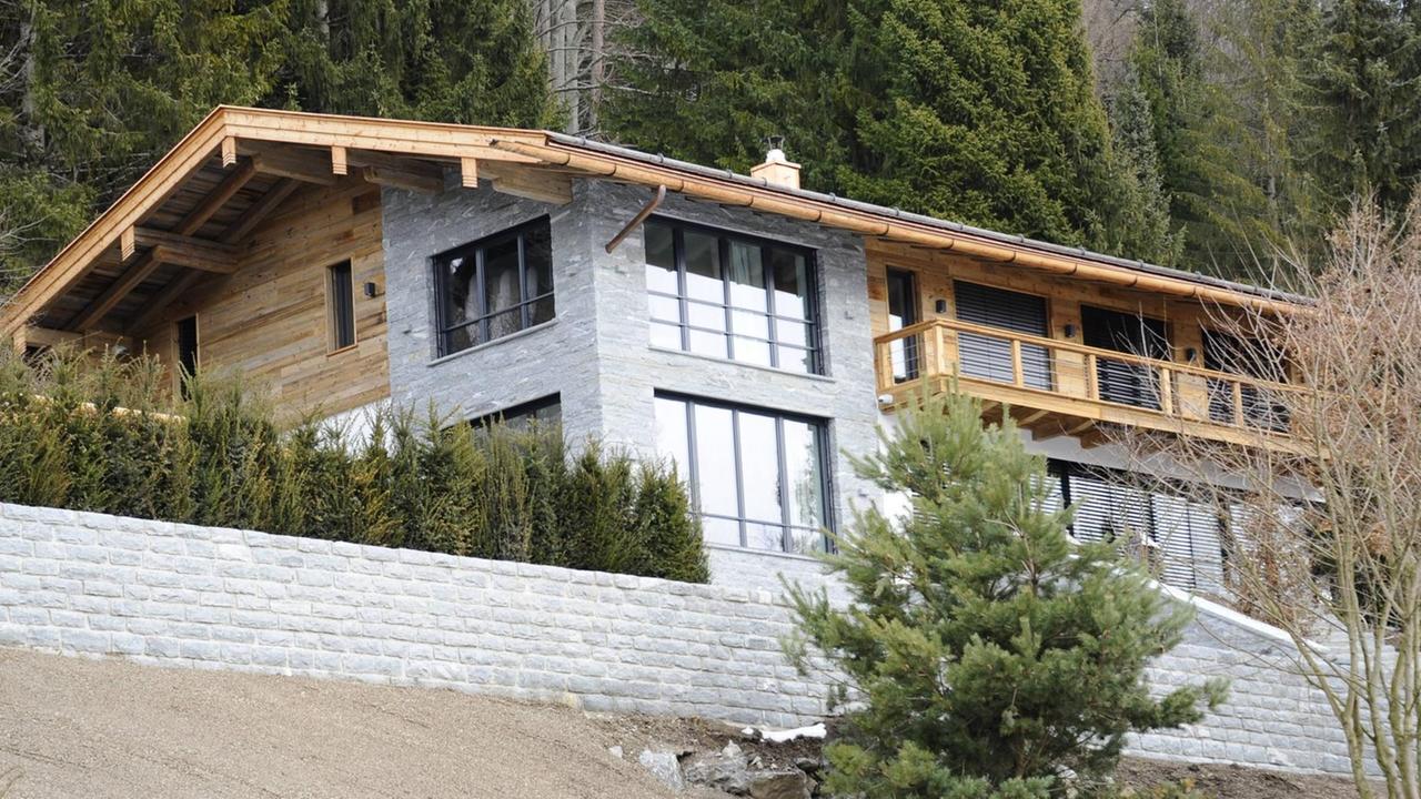 Ein geräumiges Haus aus Holz und Stein mit vielen Fenstern auf einer Anhöhe. Ein geräumiges Haus aus Holz und Stein mit vielen Fenstern auf einer Anhöhe.