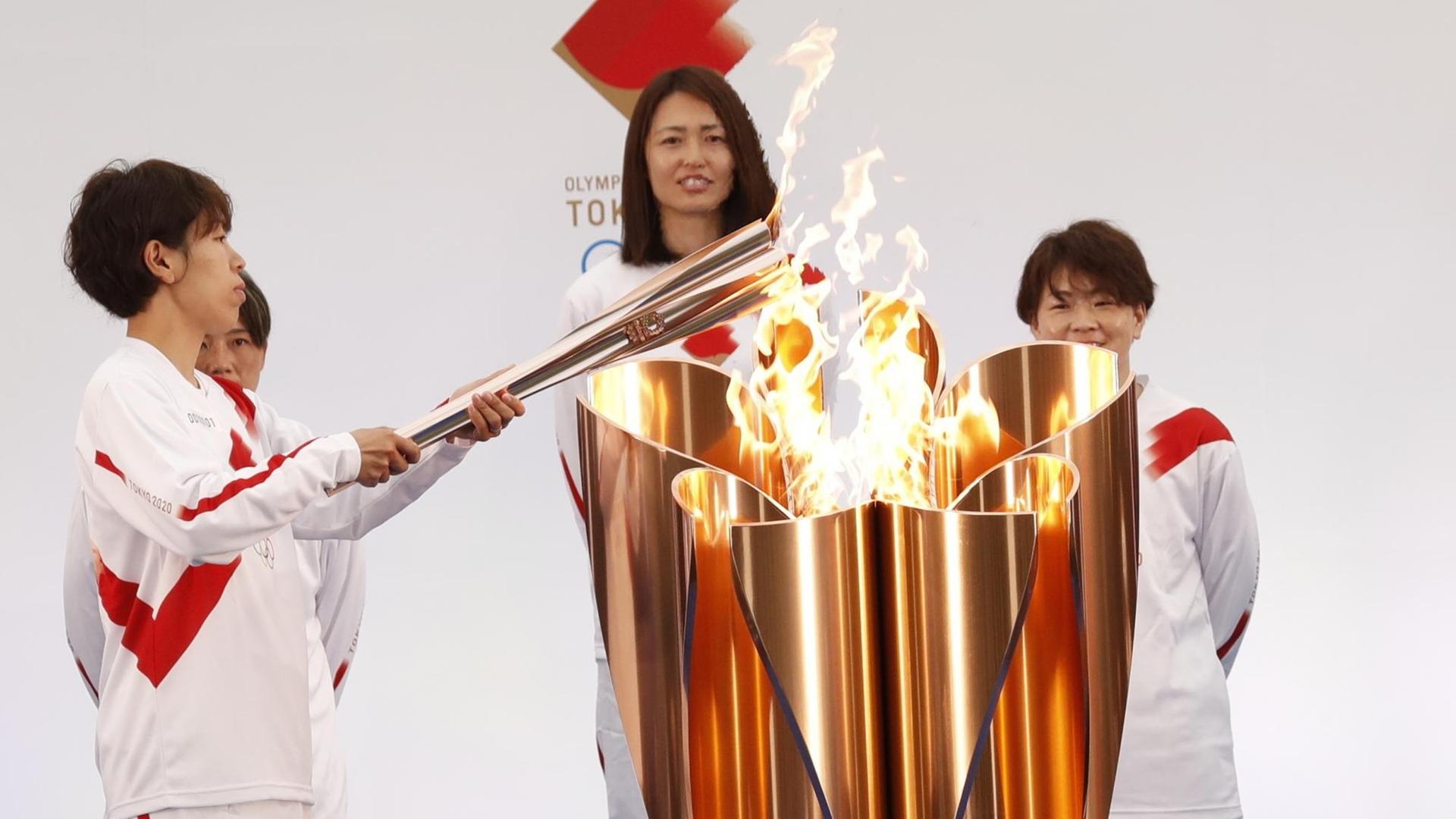Die olympische Fackel wird von einem Mitglied der japanischen Frauen-Fußball-National-Mannschaft angezündet.