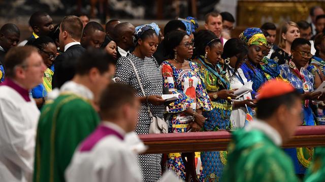 Frauen aus der Amazonas-Region stehen während der Messe in den Kirchenbänken. Daneben: Geistliche und Messdiener.