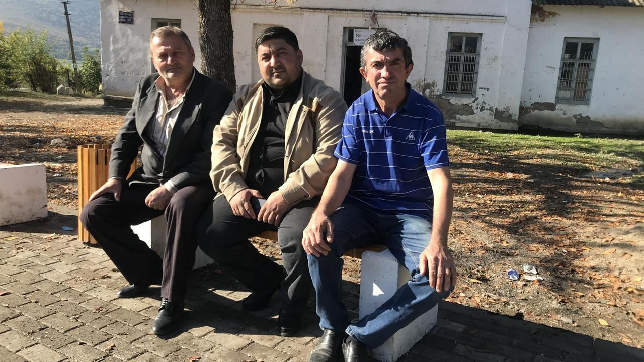 Drei Männer mit armenischen und aserbaidschanischen Wurzeln sitzen im Georgischen Dorf Tsopi zusammen auf einer Bank.