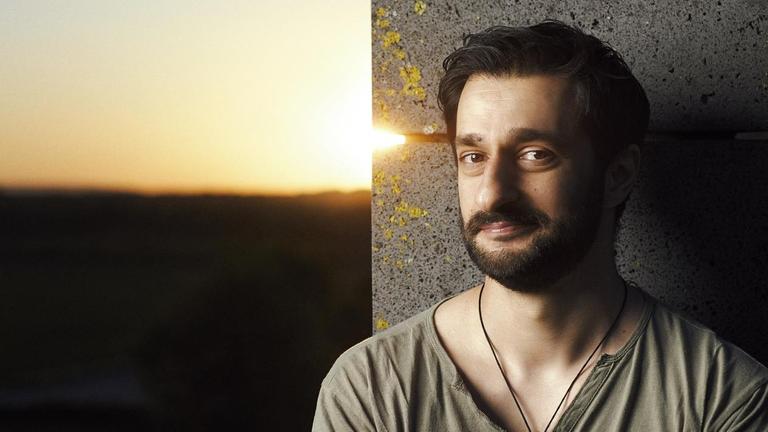Der Kabarettist Sulaiman Masomi steht mit verschränkten Armen an einer Mauer Der Kabarettist Sulaiman Masomi steht mit verschränkten Armen an einer Mauer