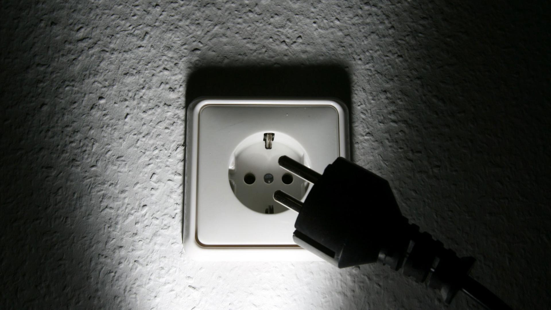 Ein schwarzer Stecker vor einer weißen 220-Volt-Steckdose aufgenommen am Dienstag (19.09.2006) in Hamburg. Ein schwarzer Stecker vor einer weißen 220-Volt-Steckdose aufgenommen am Dienstag (19.09.2006) in Hamburg.