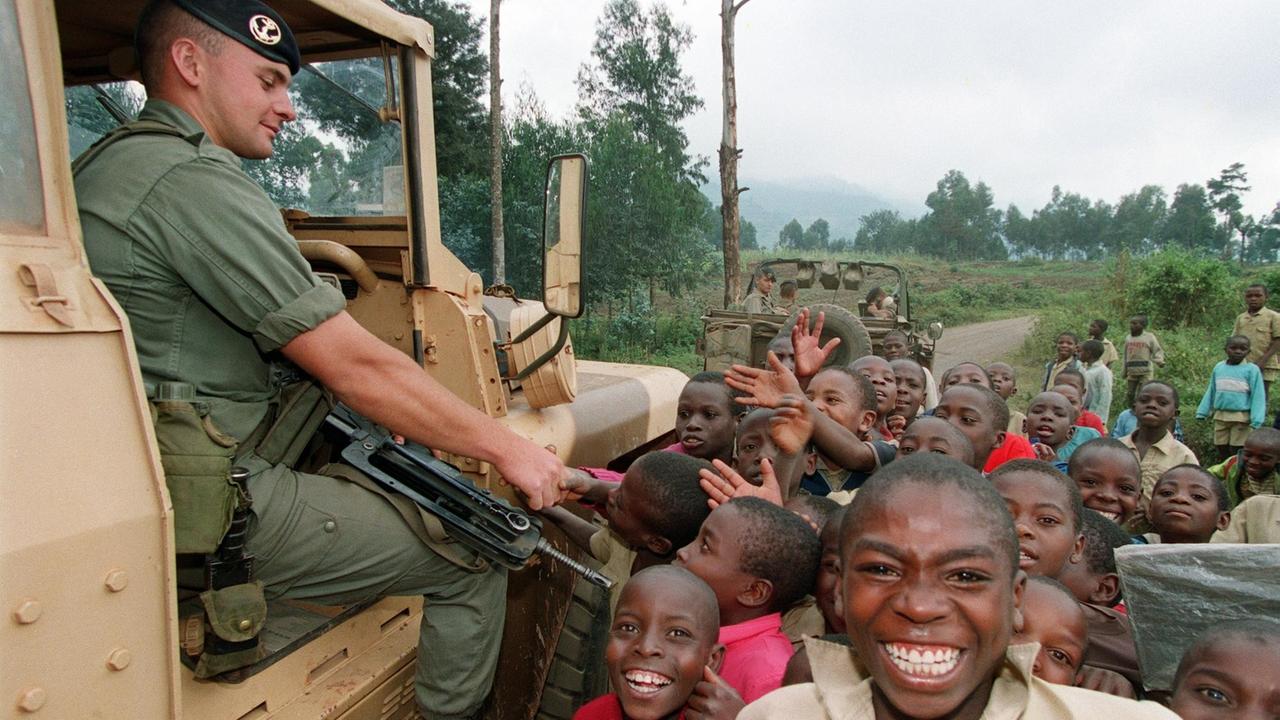 Ein französischer Soldat, der an den Operation Turquoise teilnimmt, schüttelt am 27. Juni 1994 die Hände mit Hutu-Kindern im Dorf Murutu, 60 Kilometer von der Grenze zu Zaire entfernt. Der Sicherheitsrat der Vereinten Nationen ermächtigte am 22. Juni den Einsatz der französischen Streitkräfte im Südwesten Ruandas - "Operation Turquoise". / AFP FOTO / PASCAL GUYOT