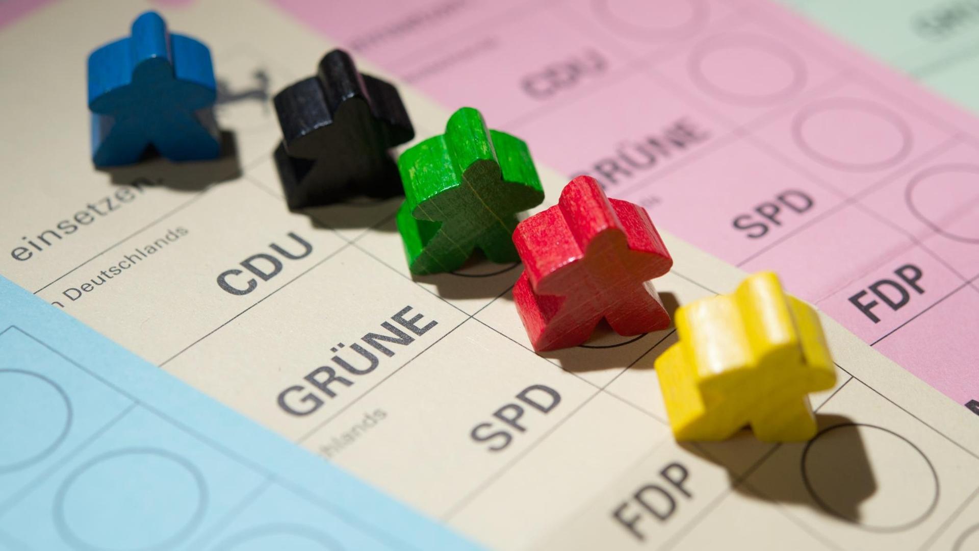 Farbige Spielfiguren stehen auf Wahlscheinen. Farbige Spielfiguren stehen auf Wahlscheinen.