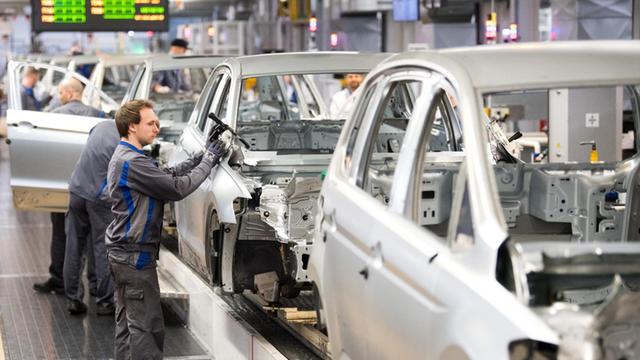 Das Bild zeigt einen Arbeiter an einem Montageband in einem VW-Werk.