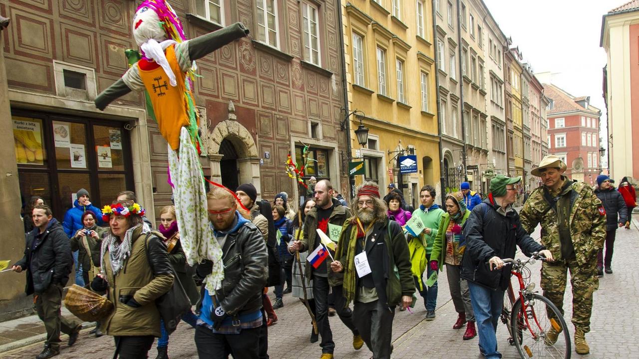 Eine Gruppe von Menschen zieht mit einer Strohpuppe durch die Altstadt von Warschau. Eine Gruppe von Menschen zieht mit einer Strohpuppe durch die Altstadt von Warschau.