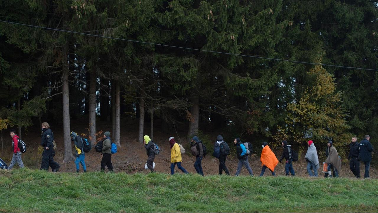 Flüchtlinge überqueren nahe Wegscheid in Bayern gemeinsam mit der Polizei die Grenze von Österreich nach Deutschland und werden zu einem Reisebus geführt.