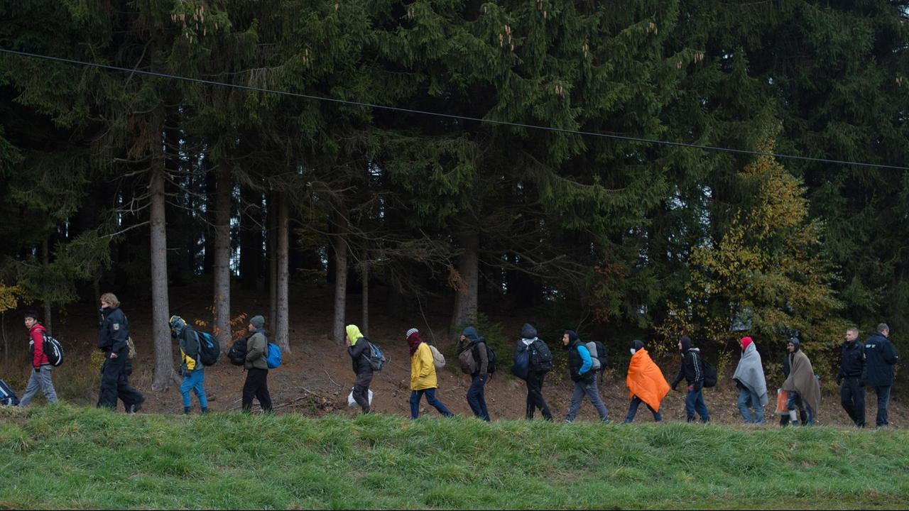 Flüchtlinge überqueren nahe Wegscheid in Bayern gemeinsam mit der Polizei die Grenze von Österreich nach Deutschland und werden zu einem Reisebus geführt. Flüchtlinge überqueren nahe Wegscheid in Bayern gemeinsam mit der Polizei die Grenze von Österreich nach Deutschland und werden zu einem Reisebus geführt.