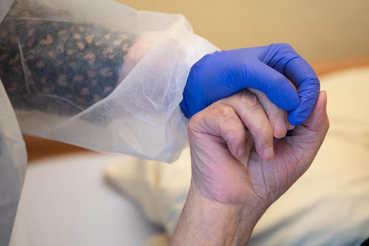 18.11.2020, Baden-Württemberg, Tübingen: Eine Altenpflegerin in Schutzausrüstunghält die Hand eines Bewohners. Foto: Sebastian Gollnow/dpa | Verwendung weltweit 18.11.2020, Baden-Württemberg, Tübingen: Eine Altenpflegerin in Schutzausrüstunghält die Hand eines Bewohners. Foto: Sebastian Gollnow/dpa | Verwendung weltweit