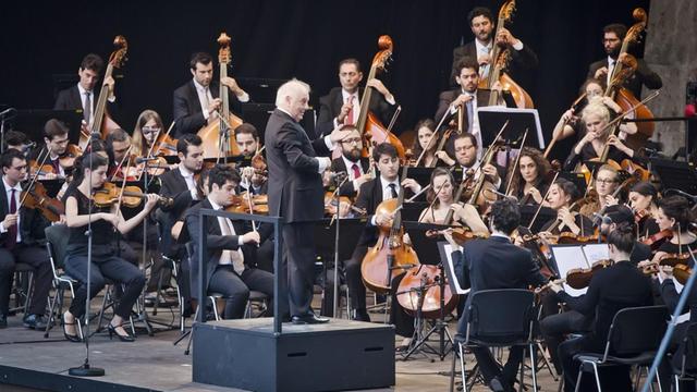 Das Foto zeigt Daniel Barenboim mit dem West-Eastern Divan Orchestra bei einem Konzert in der Berliner Waldbühne.