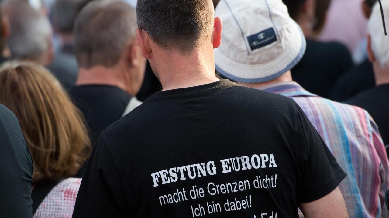 Ein Anhänger der islamfeindlichen Pegida-Bewegung trägt ein T-Shirt mit dem Aufdruck "Festung Europa macht die Grenzen dicht! Ein Anhänger der islamfeindlichen Pegida-Bewegung trägt ein T-Shirt mit dem Aufdruck "Festung Europa macht die Grenzen dicht!