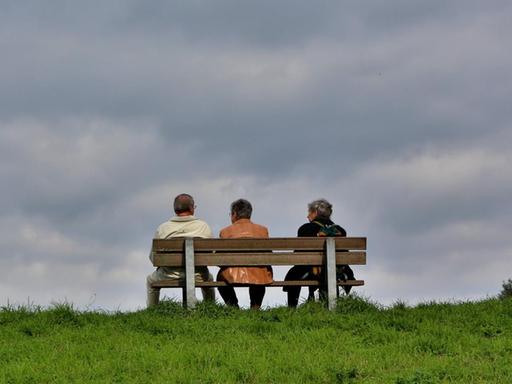 Ältere Menschen sitzen auf einer Bank.