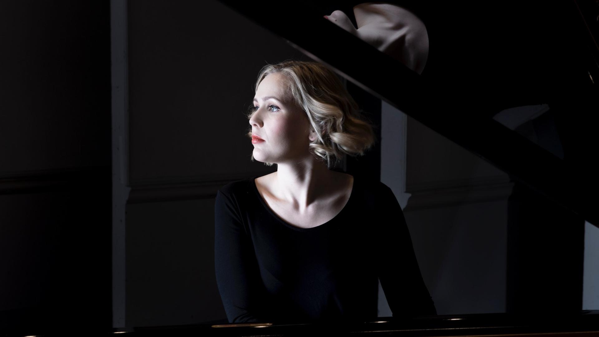 Die Pianistin sitzt am Flügel und schaut in die Ferne Die Pianistin sitzt am Flügel und schaut in die Ferne