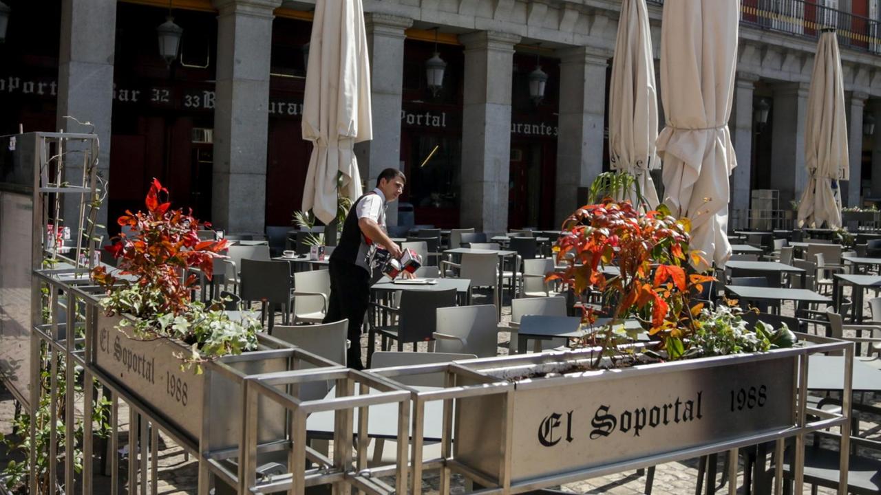 Ein Kellner schließt eine Bar auf der Plaza Mayor in Madrid. Ein Kellner schließt eine Bar auf der Plaza Mayor in Madrid.