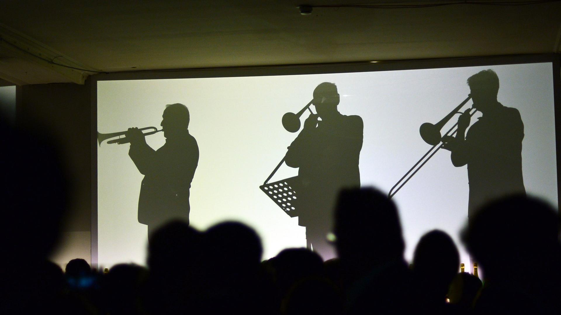 Die Silhouetten von live spielenden Orchestermusikern sind am 05.02.2014 in Berlin auf dem Champagnerempfang Moët & Chandon Grand Scores im ehemaligen Kaufhaus Jandorf auf Leinwänden zu sehen