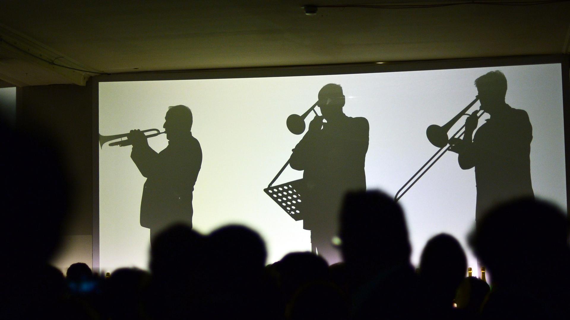 Die Silhouetten von live spielenden Orchestermusikern sind am 05.02.2014 in Berlin auf dem Champagnerempfang Moët & Chandon Grand Scores im ehemaligen Kaufhaus Jandorf auf Leinwänden zu sehen Die Silhouetten von live spielenden Orchestermusikern sind am 05.02.2014 in Berlin auf dem Champagnerempfang Moët & Chandon Grand Scores im ehemaligen Kaufhaus Jandorf auf Leinwänden zu sehen
