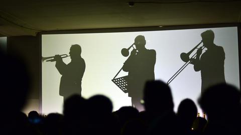 Die Silhouetten von live spielenden Orchestermusikern sind am 05.02.2014 in Berlin auf dem Champagnerempfang Moët & Chandon Grand Scores im ehemaligen Kaufhaus Jandorf auf Leinwänden zu sehen
