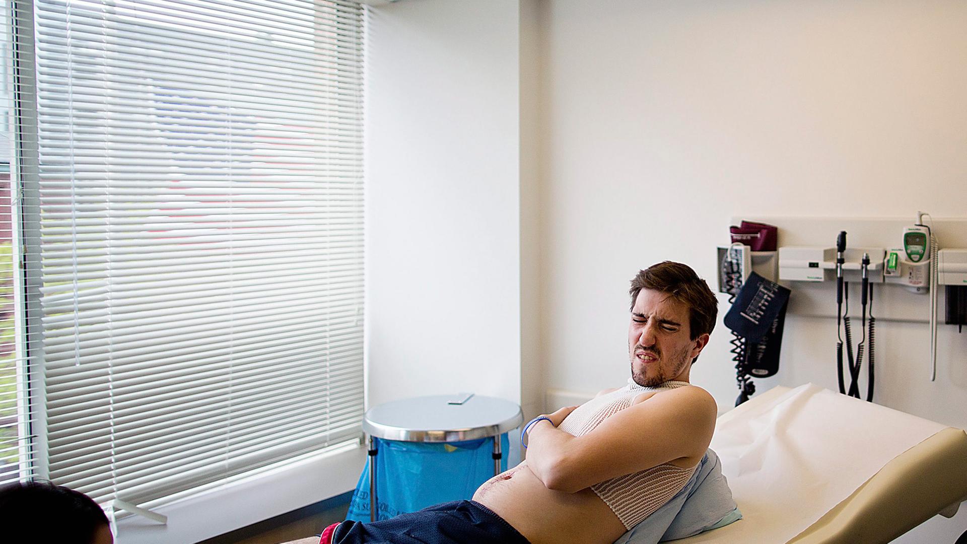 Jeff Bauman liegt nur mit kurzer Hose und Shirt bekleidet auf einer Liege in einer Reha-Klinik, ihm fehlen beide Unterschenkel, sein Gesicht zeigt Erschöpfung. Jeff Bauman liegt nur mit kurzer Hose und Shirt bekleidet auf einer Liege in einer Reha-Klinik, ihm fehlen beide Unterschenkel, sein Gesicht zeigt Erschöpfung.