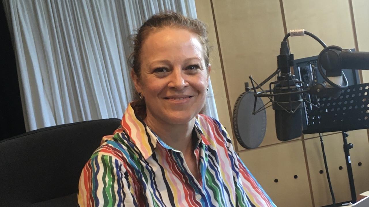 Eine Frau in buntem Hemd sitzen vor einem Radiomikrofon und lächelt in die Kamera. Eine Frau in buntem Hemd sitzen vor einem Radiomikrofon und lächelt in die Kamera.