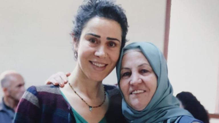 Zwei Frauen, die eine mit Kopftuch, die andere mit kurzem Haar, legen die Arme umeinander und lächeln. Zwei Frauen, die eine mit Kopftuch, die andere mit kurzem Haar, legen die Arme umeinander und lächeln.