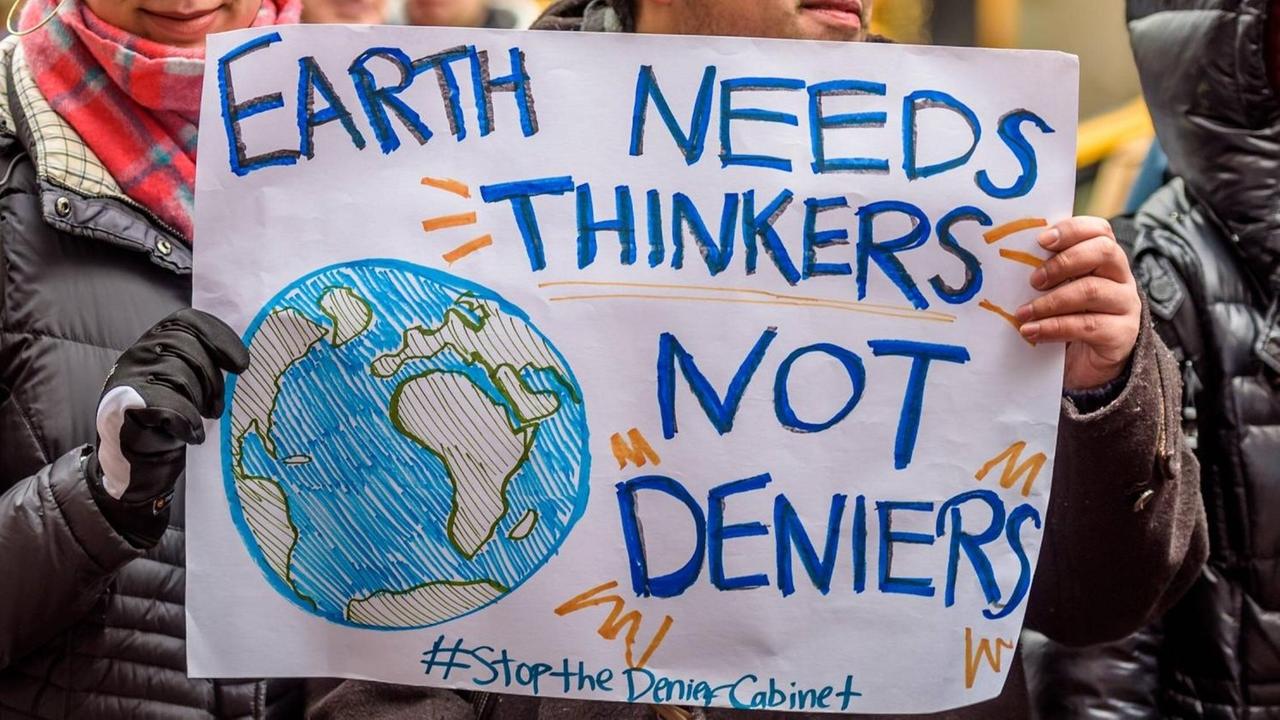 New Yorker demonstrieren gegen Trumps Kabinett, zu dem auch Personen gehören, die bestreiten, dass es einen Klimawandel gibt. Eine Frau hält ein Schild in der Hand, auf dem steht: "Earth needs thinkers not deniers". Die Erde braucht Denker, keine Leugner. New Yorker demonstrieren gegen Trumps Kabinett, zu dem auch Personen gehören, die bestreiten, dass es einen Klimawandel gibt. Eine Frau hält ein Schild in der Hand, auf dem steht: "Earth needs thinkers not deniers". Die Erde braucht Denker, keine Leugner.