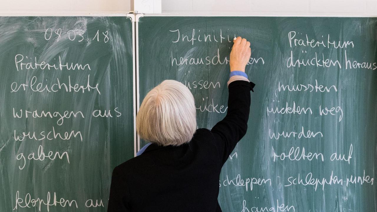 Eine Lehrerin der Oberschule an der Ronzelenstraße in Bremen steht in einem Klassenraum an einer Tafel und schreibt. Eine Lehrerin der Oberschule an der Ronzelenstraße in Bremen steht in einem Klassenraum an einer Tafel und schreibt.