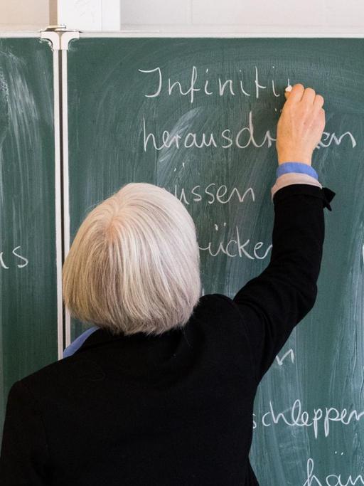 Eine Lehrerin der Oberschule an der Ronzelenstraße in Bremen steht in einem Klassenraum an einer Tafel und schreibt.