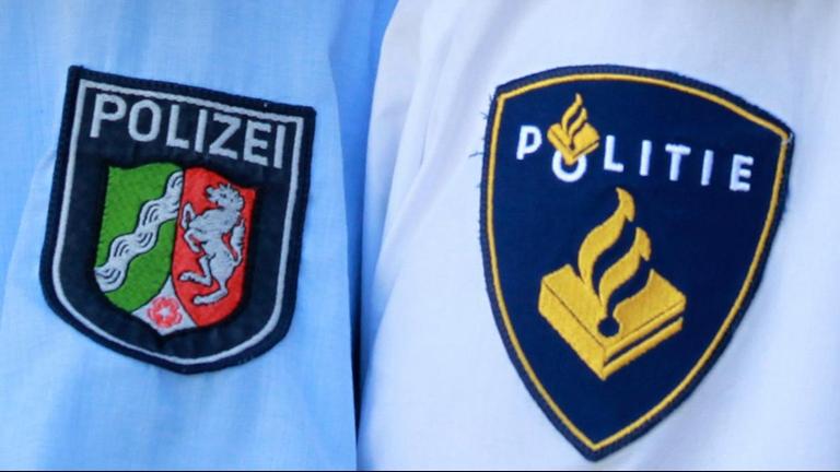 Deutsche und niederländische Polizisten posieren mit Handschellen. Deutsche und niederländische Polizisten posieren mit Handschellen.