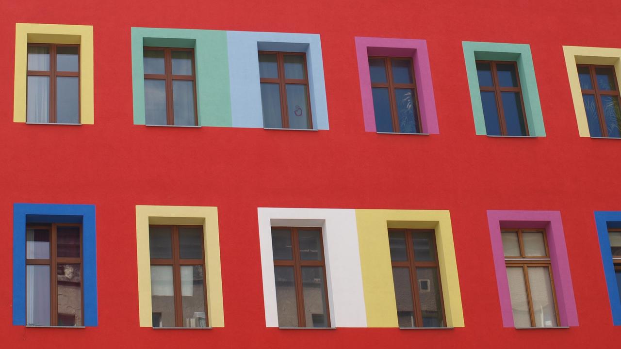Blick auf die Fassade eines Mehrfamilienhauses mit bunten Fensterrahmen. Blick auf die Fassade eines Mehrfamilienhauses mit bunten Fensterrahmen.