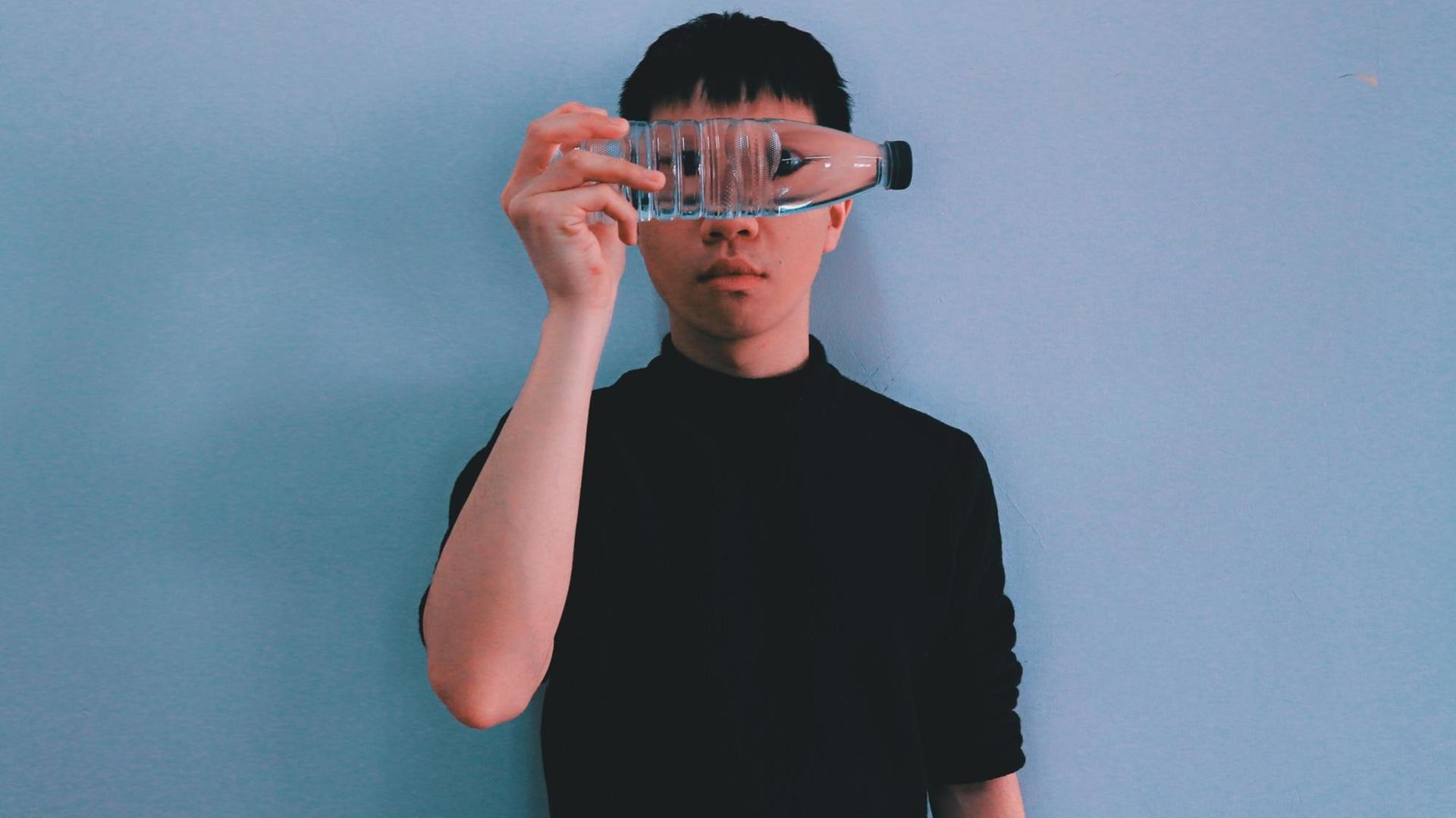 Das Bild zeigt einen Jungen, der eine durchsichtige Plastikflasche mit Wasser vor seine Augen hält. Das Bild zeigt einen Jungen, der eine durchsichtige Plastikflasche mit Wasser vor seine Augen hält.