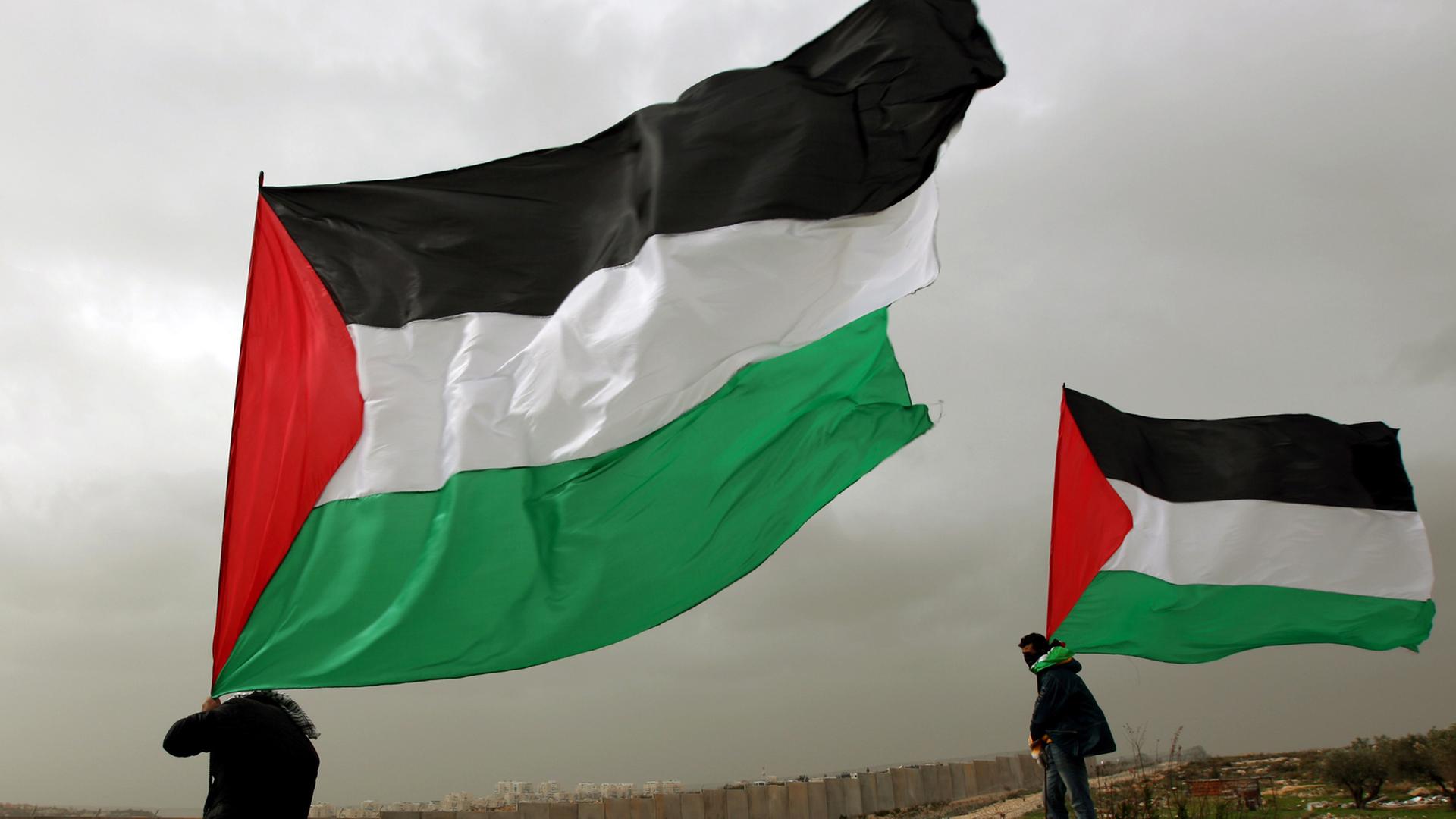 Palästinensische Aktivisten hissen die Flagge Palästinas am Grenzzaun zu Israel im Westjordanland. Palästinensische Aktivisten hissen die Flagge Palästinas am Grenzzaun zu Israel im Westjordanland.
