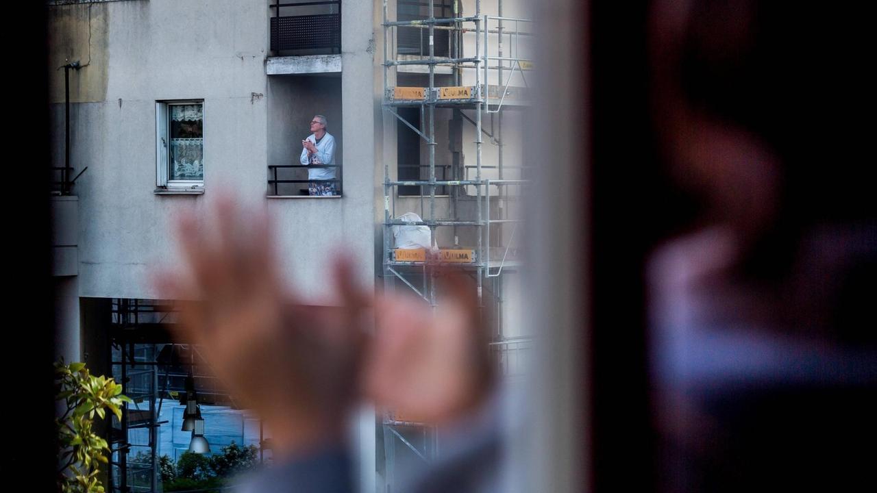 Menschen stehen am Fenster und klatschen. Menschen stehen am Fenster und klatschen.