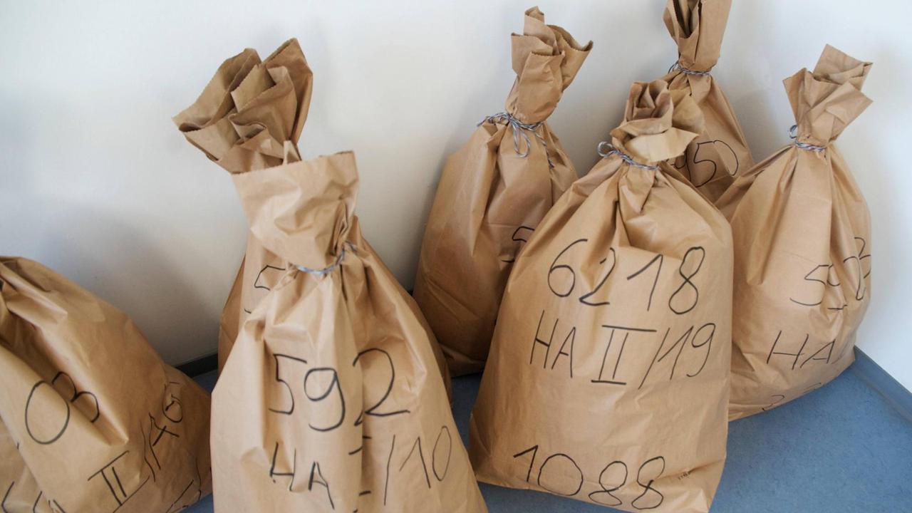 Mehrere Säcke mit Zahlen- und Buchstabencodes stehen an eine Wand gelehnt. Mehrere Säcke mit Zahlen- und Buchstabencodes stehen an eine Wand gelehnt.