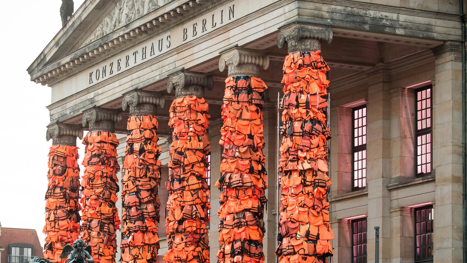 Arbeiter befestigen am 13.02.2016 am Konzerthaus am Gendarmenmarkt in Berlin zahlreiche Rettungswesten. Der chinesische Künstler Ai Weiwei will mit der Kunstinstallation an das Schicksal der vielen Flüchtlinge, die auf ihrem Weg nach Europa ertrunken sind, erinnern. Die Rettungswesten hatte er dazu von der griechischen Insel Lesbos bekommen