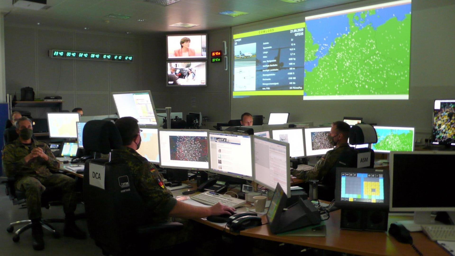 Blick ins Nationale Lage- und Führungszentrum für Sicherheit im Luftraum der Bundeswehr, in dem Menschen vor Computerbildschirmen sitzen