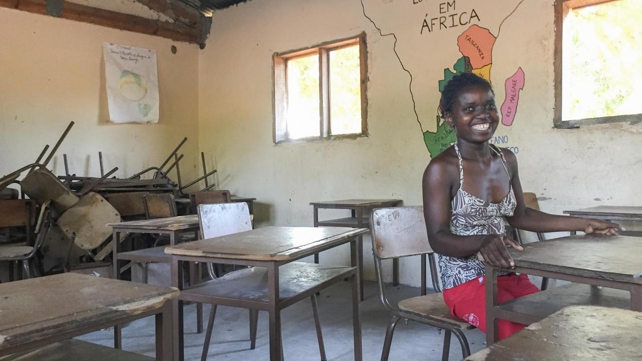 Die 26-jährige Lehrerin Anifa Armando Cao sitzt auf deiner Schulbank in der Grundschule in Chai-Chai. An der Wand hinter ihr ist eine Afrika-Karte.
