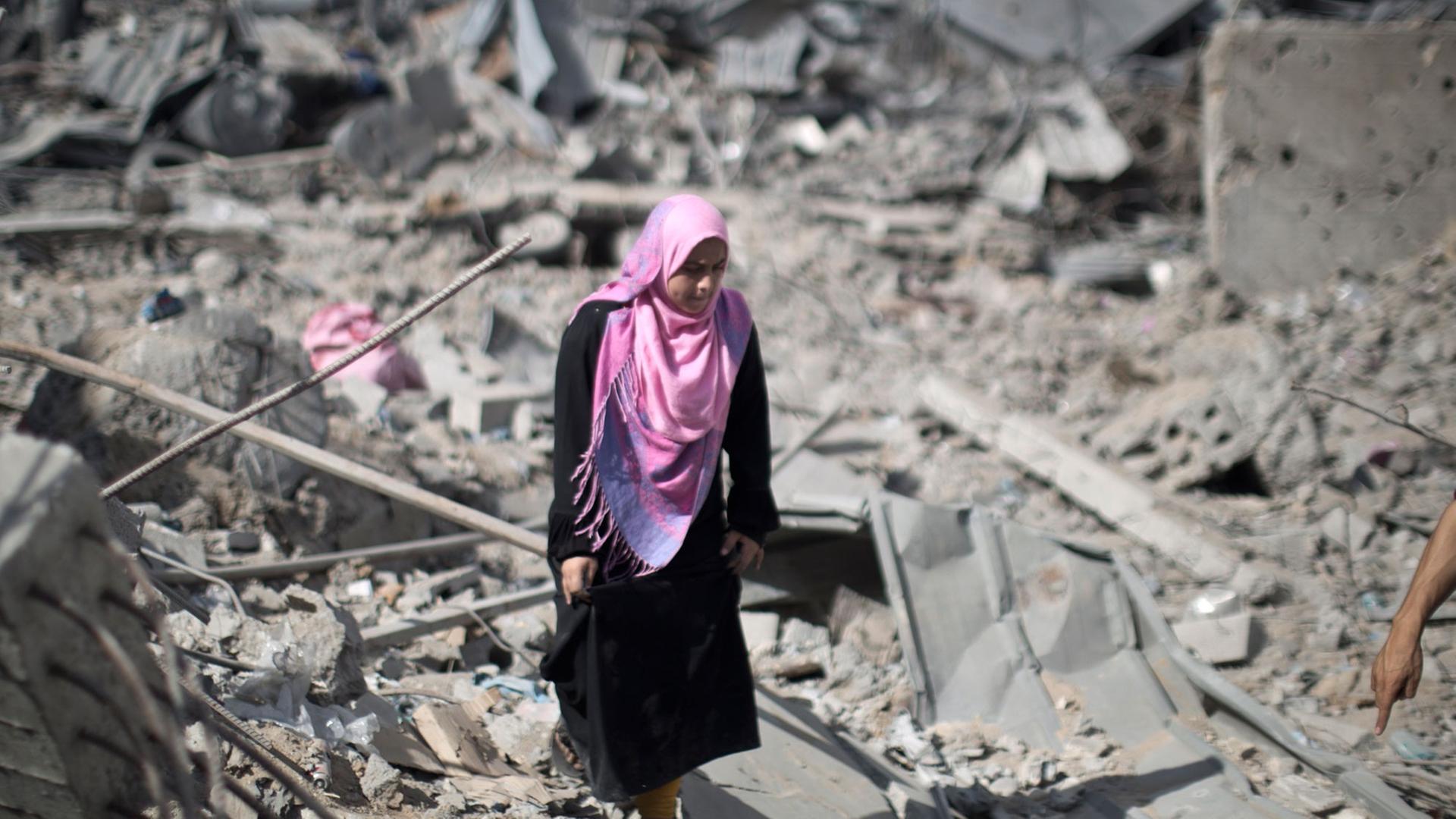 Eine palästinensische Frau läuft in Trümmern in Gaza Stadt umher. Eine palästinensische Frau läuft in Trümmern in Gaza Stadt umher.