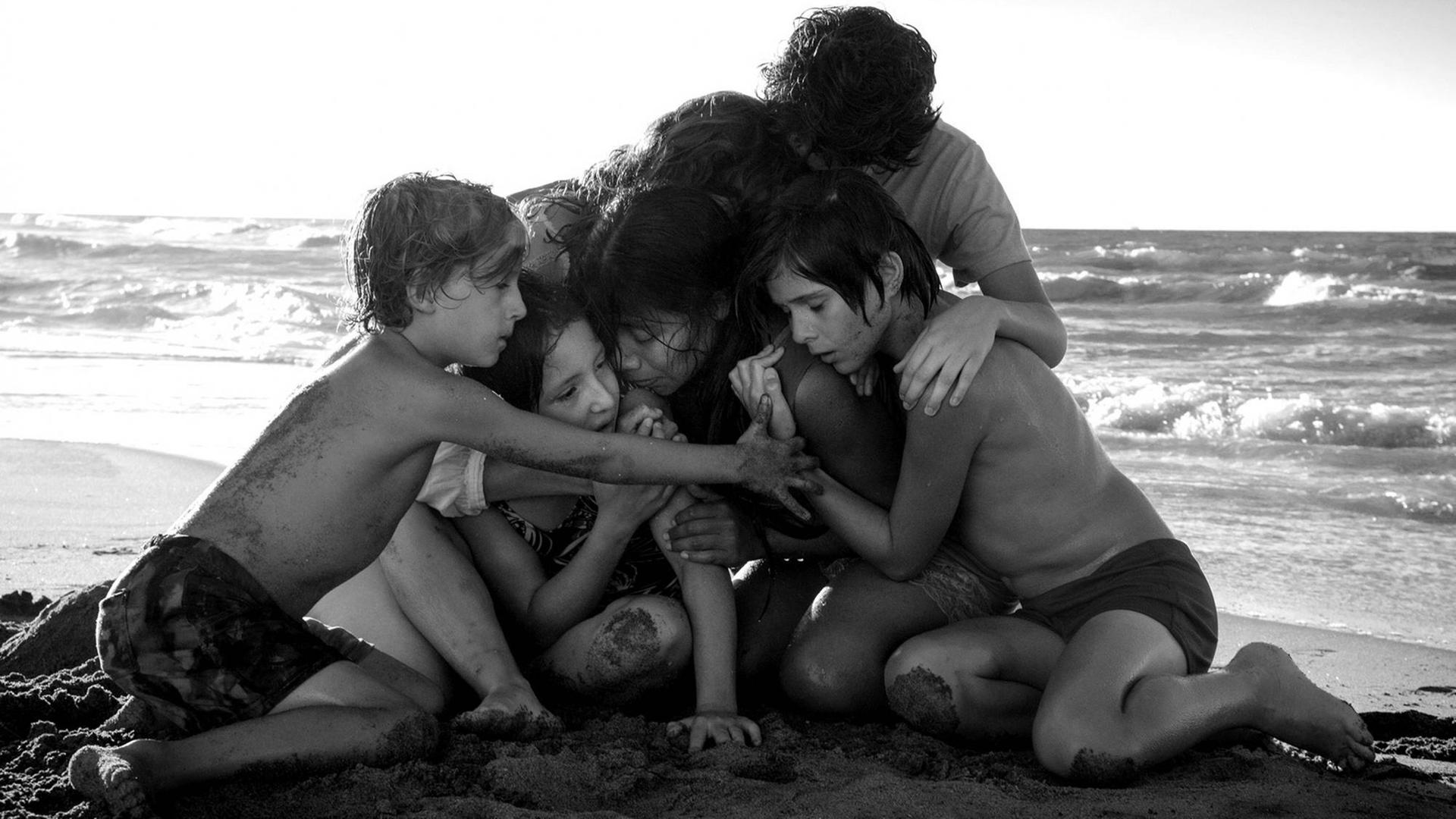 Filmszene aus Cuaróns "Roma": Die jugendlichen Hauptdarsteller kauern am Strand und umarmen sich. Filmszene aus Cuaróns "Roma": Die jugendlichen Hauptdarsteller kauern am Strand und umarmen sich.