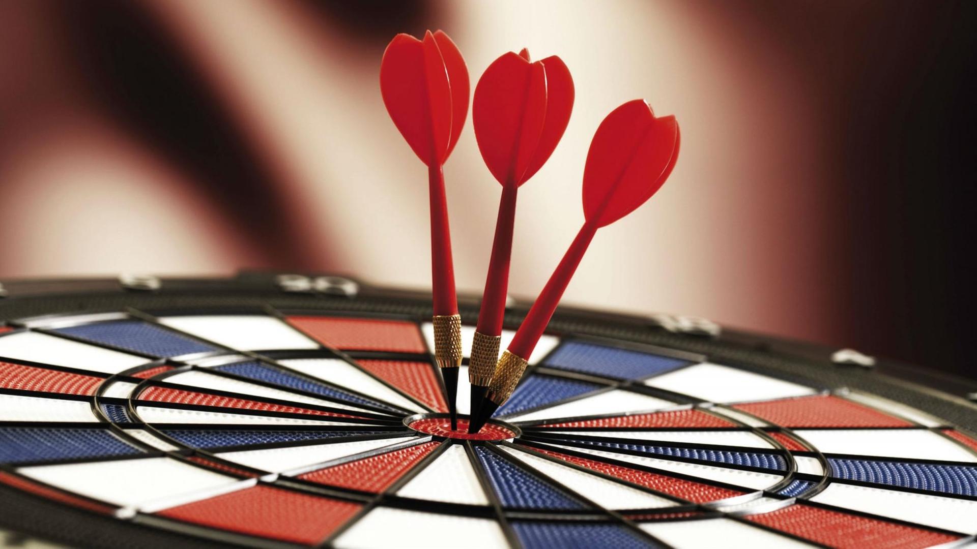 Drei Dartpfeile in der Mitte einer Dartscheibe (Nahaufnahme). Drei Dartpfeile in der Mitte einer Dartscheibe (Nahaufnahme).