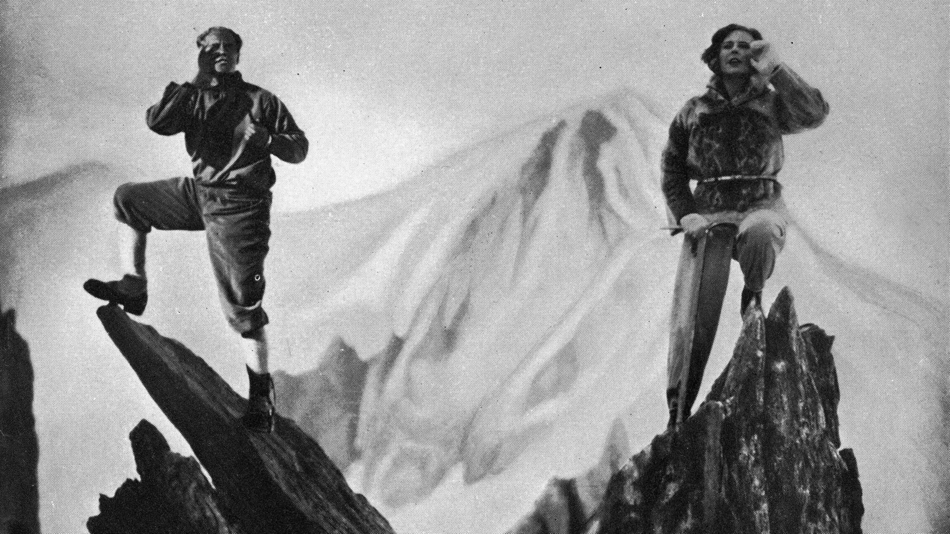 Filmstill: Blick auf die Berge. Im Vordergrund links Sepp Rist, rechts Leni Riefenstahl auf einer Felsspitze Filmstill: Blick auf die Berge. Im Vordergrund links Sepp Rist, rechts Leni Riefenstahl auf einer Felsspitze