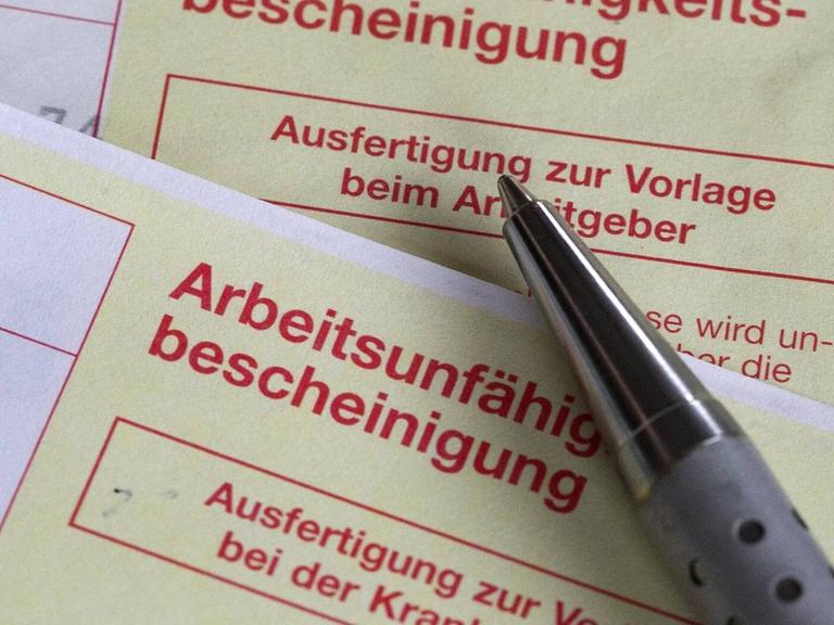 Zu sehen sind zwei Arbeitsunfähigkeitsbescheinigungen - eine zur Vorlage bei der Krankenasse und eine andere zur Vorlage beim Arbeitgeber.