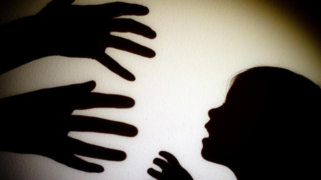 Das Bild zeigt Schattenrisse von drohenden Händen eines Erwachsenen und den Schatten eines Kinderkopfes.