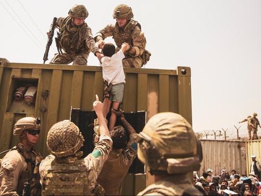 Britische Koalitionstruppen, türkische Koalitionstruppen und US-Marines helfen einem Kind während einer Evakuierung am internationalen Flughafen Hamid Karzai in Kabul.