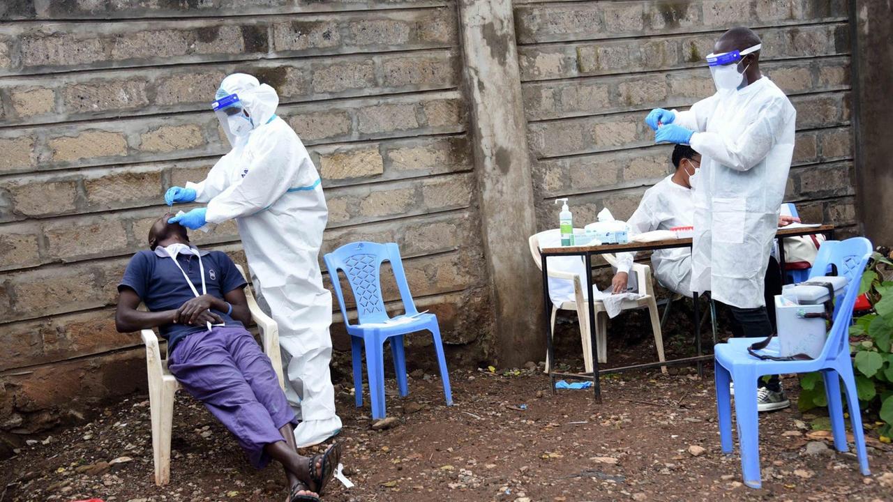 Medizinisches Personal führt auf einfachen Plastikstühlen und -Tischen Massentests auf COVID-19 im Slum von Kawangware in Nairobi durch Medizinisches Personal führt auf einfachen Plastikstühlen und -Tischen Massentests auf COVID-19 im Slum von Kawangware in Nairobi durch