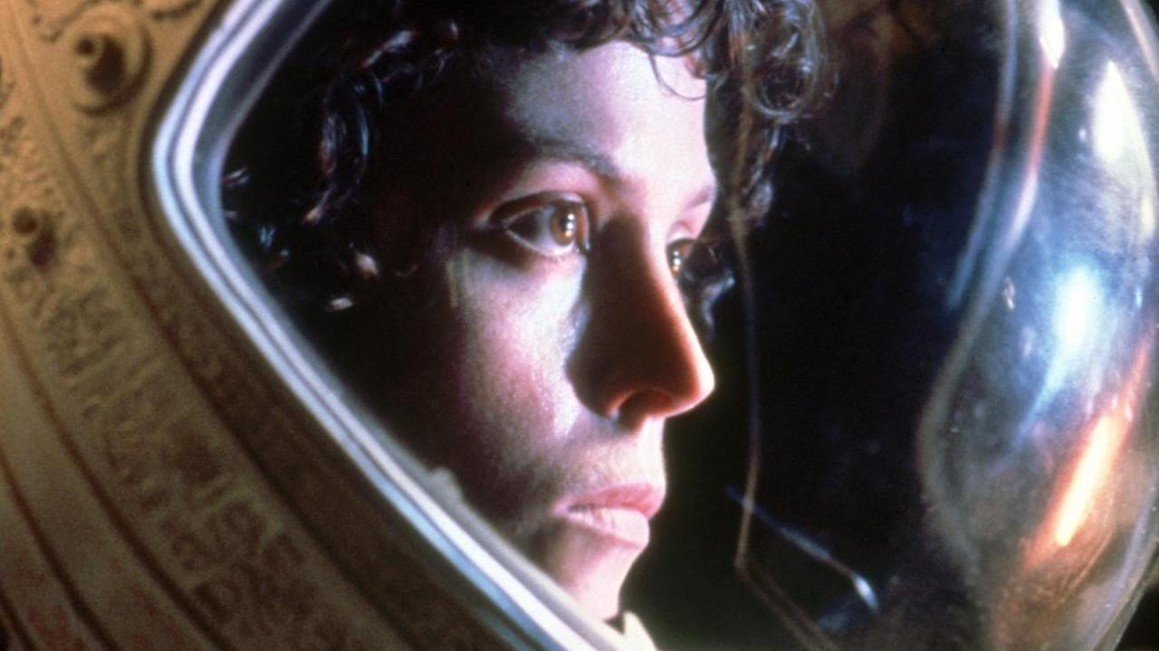 Sigourney Weavers Gesicht durch einen Astronauten-Helm zu sehen.