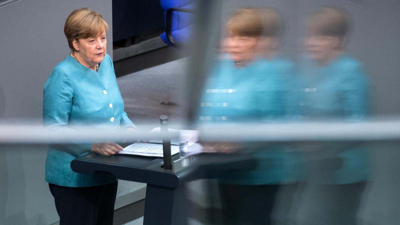 Angela Merkel steht in einem hellblauen Blazer am Rednerpult des Bundestags. Angela Merkel steht in einem hellblauen Blazer am Rednerpult des Bundestags.