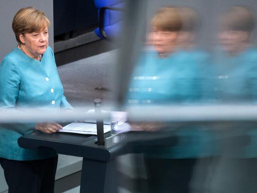 Angela Merkel steht in einem hellblauen Blazer am Rednerpult des Bundestags.