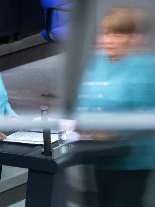 Angela Merkel steht in einem hellblauen Blazer am Rednerpult des Bundestags.