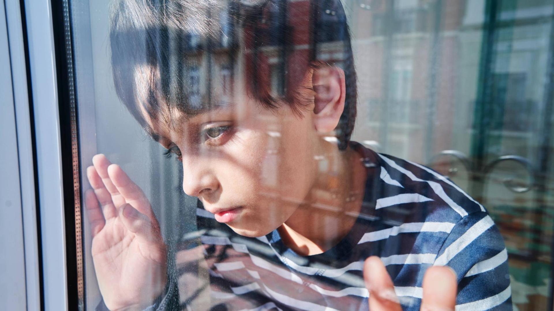 Ein Junge schaut unglücklich aus dem Fenster. (Symbolfoto) Ein Junge schaut unglücklich aus dem Fenster. (Symbolfoto)